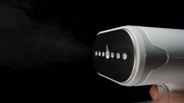 Elde tutulan Buharlı Buhar Buharlı Buhar Jeti Siyah Arkaplan ve Metalik Yüzey Yansıması Üzerine Yavaş Çekimde Su Damlacıkları