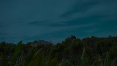 Yoğun Yeşillik ve Siluetli Dağ Sırtı ile Tropikal Zaman Hızı Sahnesinde Gece Dönüşümleri Gibi Fırtınalı Bulutlar Yavaşça Dönüşüyor