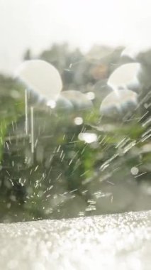 Dikey video. Beyaz Yüzeyde Parlak Mercek Alevleri ve Yumuşak Arkaplanlı Dramatik Su Damlacıkları Yavaş Çekimde Patlıyor