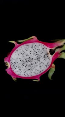 Dikey video. Beyaz Et ve Siyah Tohumlu Yarı Ejder Meyvesi Üst Görünümü Siyah Arkaplanda Kusursuz Dönüşümlü