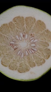 Dikey video. Soluk Sarı Parçalar ve Tohumlar ile Pomelo Çapraz Bölümü Üst Görünümü Kusursuz Dönüşümlü Siyah Arkaplanda İzole