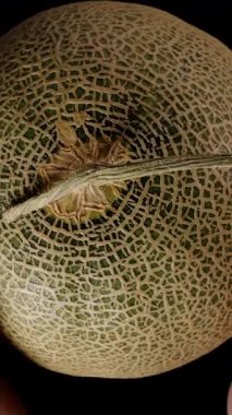 Dikey video. Bir Kavunu İki El Ayırarak Sulu Portakal İçini ve Yarısı Meyvelerin Tohum Çukuru 'nu Karanlık Arkaplanla Yakın Çekimde Ortaya Çıkartıyor