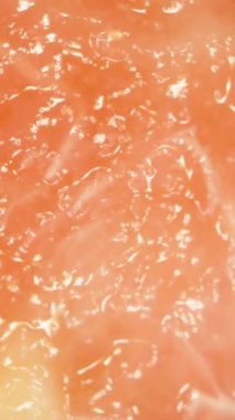 Dikey video. Yumuşak Odaklı Yumuşak Hareket ve Işık Yansıması ile Yumuşak Şeffaf Doku ve İplikleri Gösteren Pembe Guava Etinin Dönen Makro Yakın Çekimi