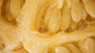 Yumuşak dokusu ve kıvrımlı kıvrımlı kıvrımlı kıvrımlı kıvrımlı ete gömülmüş Karpuz İçinin Dönen Makro Yakın Çekimi Parlak Sarı Tohumlar