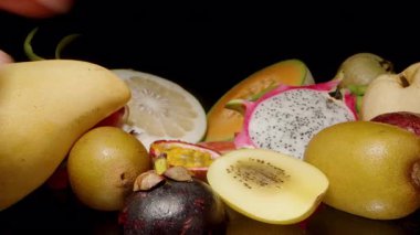 Kivi, Ejderha Meyvesi ve Tutku Meyvesi dahil olmak üzere çeşitli tropikal meyvelere uzanan ve dokunan İki Elin Dolly Kaydırıcı Yakın Çekimi