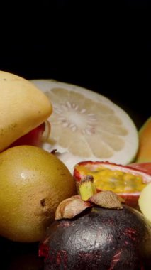 Dikey video. Kivi, Ejderha Meyvesi ve Tutku Meyvesi dahil olmak üzere çeşitli tropikal meyvelere uzanan ve dokunan İki Elin Dolly Kaydırıcı Yakın Çekimi