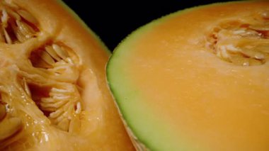 İki Kavunlu Kavun 'un Dolly Kaydırma Çekirdeği Siyah Arkaplana Karşı Dokulu Kabuk ve Temiz Kesikli Sulu Portakal ve Tohum Çekirdeğini Gösteriyor