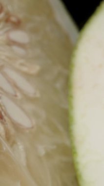 Dikey video. Siyah Arkaplana Karşı Simetrik Düzenlemede Soluk Şeffaf Bölümleri ve Beyaz Kabuğu Gösteren İki Pomelo Yarısının Dolly Kaydırma Kapanışı