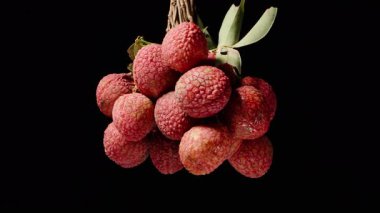 Terkedilmiş Kara Arkaplan 'a Karşı Kusursuz Döngüde Dönen Yapraklarla Olgun Meyveler Kümesi, dramatik ışıklandırma, Tropikal Hasat ve Egzotik Meyve Konsepti ile yakın plan çekimleri