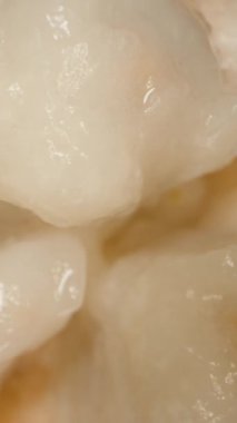 Dikey video. Santol Yarı Dönüyor ve Yavaş Yavaş Aşağı Çekiliyor, Sulu Beyaz Pulp Odakta, Makro 'da Üst Görünüm, Düşen Hareket Etkisi, Egzotik Meyve Konsepti