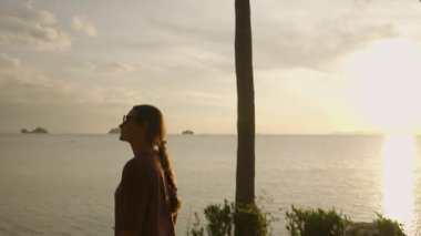 Güneş Gözlüklü Kadın Gün Batımında Sahilde Yürüyor Su Üzerine Altın Yansımalar, Huzurlu Gezinti Konseptiyle