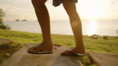 Gün batımında Palm Shadows ve Sea Reflections ile Sahil Yolu 'nda Yürüyen Parmak İzi Giyen Kişi Sahil Hayatı Konsepti