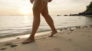 Gün batımı arkasında parıldarken Küçük Kayalıklarla Kumsalda Yürüyen Kadın Rahatlamış Ada Akşam Konsepti