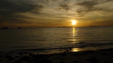 Yumuşak Altın Işık, Sakin Dalgalara Yansıyan Kişi Sahilde Sunset ve Uzak Adalar Arkaplanında, Huzurlu Gece Yürüyüşü Konsepti ile Gezinirken