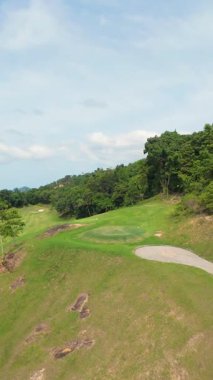Dikey video. FPV Drone, Güneşli Ada Günü 'nde Palm Trees ve Hills ile Tropikal Golf Sahasında Alçaktan Uçuyor