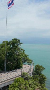 Dikey video. Cliffside Viewpoint 'te Duran Kadın Tropikal Sahile Bakıyor Rocky Hill' de Tayland Bayrağı ve Koh Samui 'de Okyanus Arkaplanda