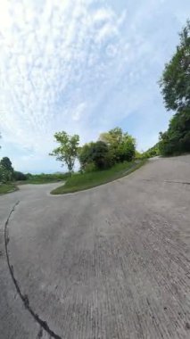 Dikey video. Virajlı Dağ Yolu 'nda Scooter sürerken Erkek ve Kadın Dönüşe Yaslanıyor Dinamik Geniş Açı Açı' yla çevrili Yoğun Ağaçlar Yüksek Hızlı Seyahat Macerası Konseptini temsil ediyor