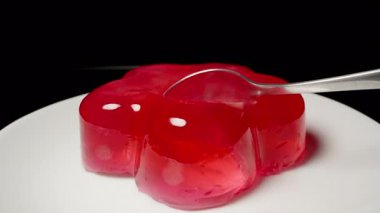 Kaşık Sıçratma Kırmızı Jöle Parlak Yüzeyli Tabak, Yan Kapanış Görünümü ve Karanlık Arkaplan, Tatlı Hizmeti Konsepti