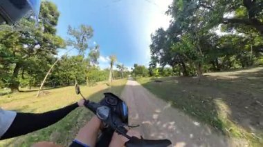 Scooter 'ın Sunny Orchard' da Ağaç Kenarlı Yol 'da Sürüşünün İlk Görüntüsü Tropikal Motor Seyahat Konseptini Sunar