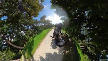 Orman yolunda yokuş yukarı giden Scooter 'lı çift Tropikal Doğa Yolculuğu Konseptini temsil eden Küçük Gezegen Efekti ile yakalandı