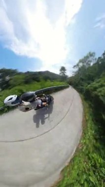 Dikey video. Hızlı Yolculuk ve Keşif Konseptini sunan Küçük Gezegen Etkisi ile Dağ Yolu 'nda Scooter kullanan çift