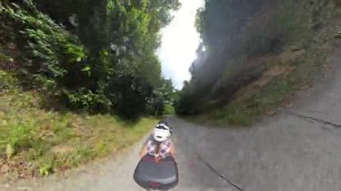 Scooter 'daki kadın ve adam yokuş aşağı gidiyor Yoğun Orman' da Dik Yol 'da İlk Kişi Açısı' nda Dar Yol 'a yaslanan Ağaçlarla