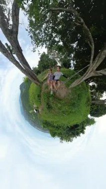 Dikey video. Minik Gezegen Kamera Efekti ile Okyanusa ve Tepelere Bakan Çift