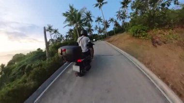 Gün batımında Palm Tree Yolu boyunca Scooter kullanan adam Arka Açı 'dan Yakalandı