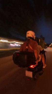 Dikey video. Gece Şehir Yolunda Yüksek Hızda Scooter süren çift Hareket Bulanık İzleme Efekti