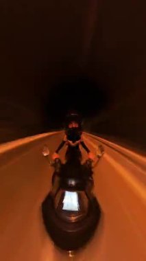 Dikey video. Gece Scooter süren adam Hız Bulanıklığı ve Miğfer Yansıması ile İlk Perspektiften Yakalandı