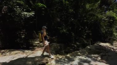 Sarı Sırt çantalı Kadın Güneş Işığı Kayalıklarında Yürüyüş Orman Temizliği, Yan Görünüm, Doğa Seyahati Konsepti