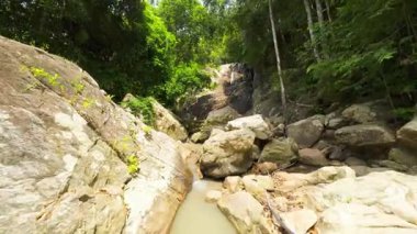 İnsansız hava aracı akıntıya karşı uçuyor Rocky Ormanı 'ndan Nehir yatağı Orman, Düşük Açı İzleme Çekimi, Tayland Konseptiyle çevrili Şelaleye doğru