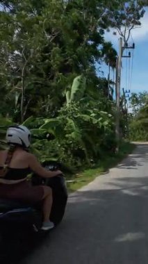 Dikey video. Mayo giyen kadın mayo giyiyor, Sunny Beton Yolu boyunca ilerliyor, Yeşil Orman, Yan Takip Açısı, Tayland Samui Adası Seyahat Konsepti