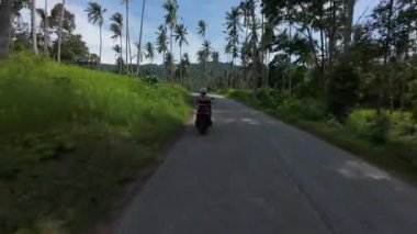 Orman Yolu 'nda scooter süren kadının arka görüntüsü Yüksek Çimen ve Uzun Palmiyeler, Yoldaki Hafif Kavis, Tayland Samui Adası Seyahat Konsepti