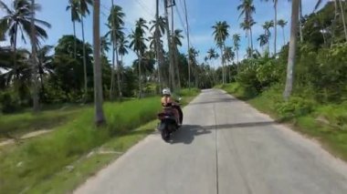 Scooter 'la İHA' dan geçen kadın Palm Trees ve Road, Dynamic Rising Motion, Tayland Samui Adası Seyahat Konsepti ile Tropikal Ada Manzarası 'na hızla yükseliyor.
