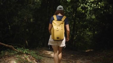 Kadın, Tayland 'da Sarı Sırt Çantası ile Karanlık Orman Yoluna Girerken Işık Ağaçların Arkasından, Arka Ön Görüş, Düşük Işık Ayarları, Doğada Yalnızlık Konsepti