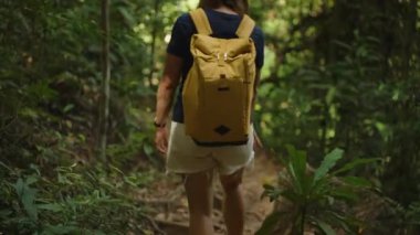 Sarı Sırt Sırtlı Kadın Tayland 'da Yoğun Ormanda Yürüyor Etrafı Tropikal Yapraklar ve Ağaçlarla çevrili, Arkadan Vurulan Orta Yol, Çevre Macerası Konsepti