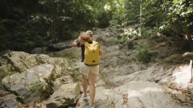 Genç Kadın Tayland 'da Sarı Sırt çantasıyla Büyük Orman Kayalıklarına Tırmanır, Arka Görüş, Parlak Gün Işığı, Yukarı Doğru Yürüyüş Yolu, Açık Hava Macerası Konsepti