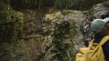 Tropikal Orman 'daki Kadın Yürüyüşçü Tayland' daki Uzun Uçurumu Gözlemlerken Kamera onun içinden Kaya Yüzeyi, Parlak Doğal Işıkta Arka Görünüm, Meydan Okuma ve Ölçek Kavramı