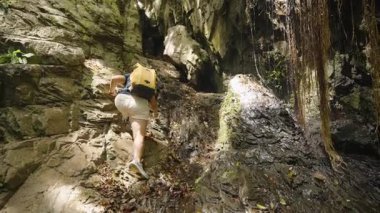 Sarı Sırt çantalı Kadın Kayalık Yol 'a Yükseliyor Gölgeli Mağara' ya Açılıyor Parlak Gün Işığıyla çevrili Orman, Geniş Açı, Keşif Kavramı ve Doğal Mucize