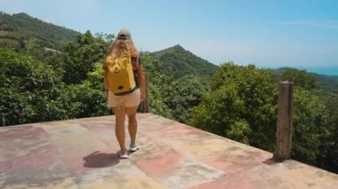 Sarı Sırt Sırtlı Kadın Platformun Sınırına Doğru Yürüyor Etrafı Okyanus ve Dağlarla çevrili, Arka Görüş, Geniş Açı, Keşif ve Özgürlük Konsepti