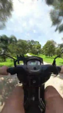 Dikey video. Scooter Sürücüsü Orman Yolunda Hızlıca İlerliyor İlk Kişi Görünümü 'nden Hareket Bulanıklığı, Tayland' da Hız Macerası ve Tropikal Keşif Konsepti