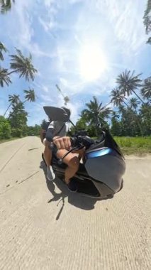Dikey video. Scooter 'lı Sürücü Palm Forest' ta Sürerken 360 Derece Kamera, Arka Görüş Perspektifi, Açık Hava Keşfi ve Tropikal Yolculuk Konsepti