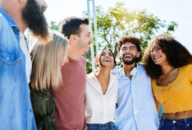 Genç bir grup mutlu arkadaş dışarıda birlikte gülerek eğleniyor. Hipster milenyumu gençleri, boş zamanlarında birbirlerine sarılmaktan zevk alıyorlar.