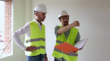 Genç inşaat mühendisi inşaat alanındaki mimar işçiyle konuşuyor.