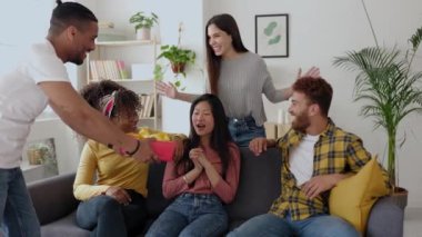 Çok ırklı bir grup genç, Asyalı arkadaşlarına doğum günü hediyesi vererek kutluyor. Yüksek kalite 4k görüntü