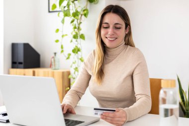 İnternet üzerinden alışveriş yapmak için kredi kartı tutan mutlu genç bir bayanla çevrimiçi ödeme konsepti.
