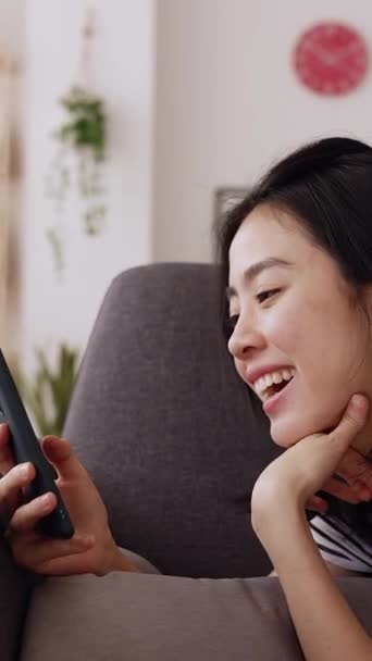 Tiro Vertical Mujer Asiática Joven Que Relaja Sofá Usando Teléfono — Vídeos de Stock