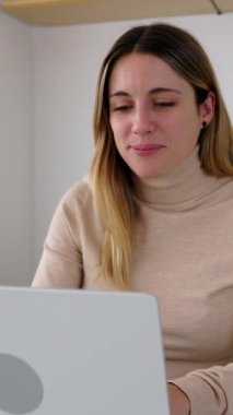 Evdeki laptopunu kullanan mutlu Latin kadının dikey görüntüsü. Teknoloji ve insanlar kavramı