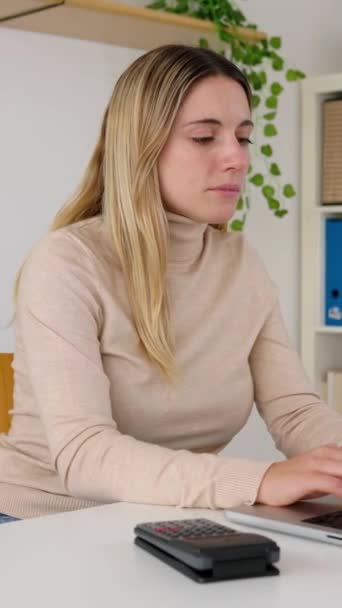 年轻女企业会计坐在总公司用笔记本电脑上网时使用计算器的垂直画面 企业家 金融和经济概念 — 图库视频影像